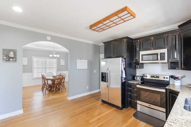 kitchen featuring arched walkways, stainless steel appliances, ornamental molding, and light wood-style flooring