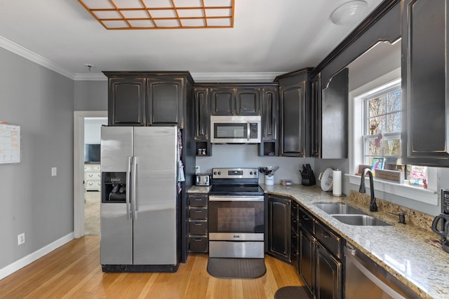 kitchen featuring a sink, light wood-style floors, ornamental molding, appliances with stainless steel finishes, and light stone countertops