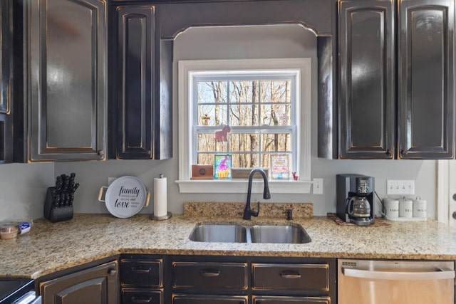 kitchen featuring dishwasher, a sink, and light stone countertops