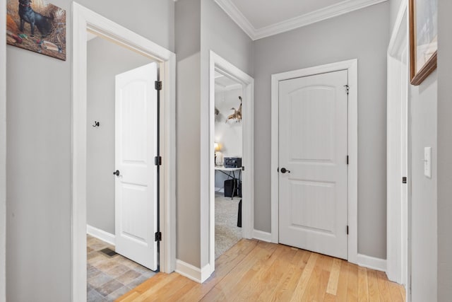 hall with ornamental molding, light wood-type flooring, and baseboards