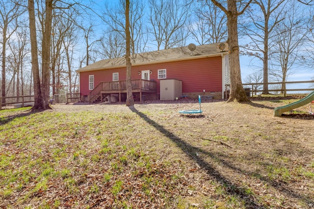 back of property with a deck, an outbuilding, a storage shed, fence, and a lawn