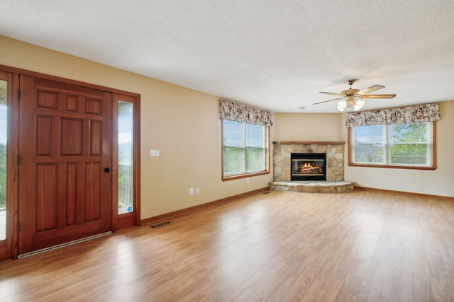 unfurnished living room featuring a textured ceiling, a wealth of natural light, wood finished floors, and visible vents