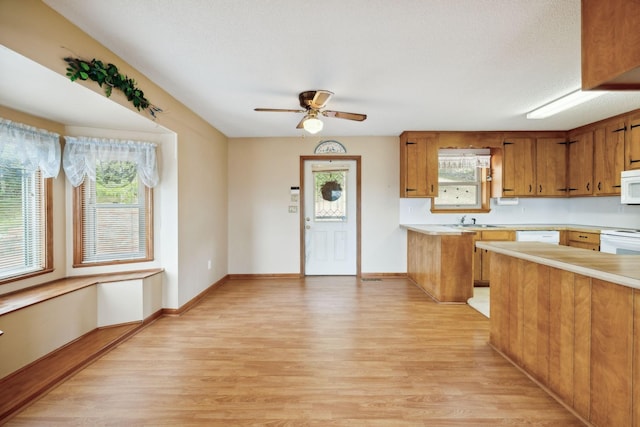 kitchen with light wood finished floors, light countertops, white microwave, and brown cabinets