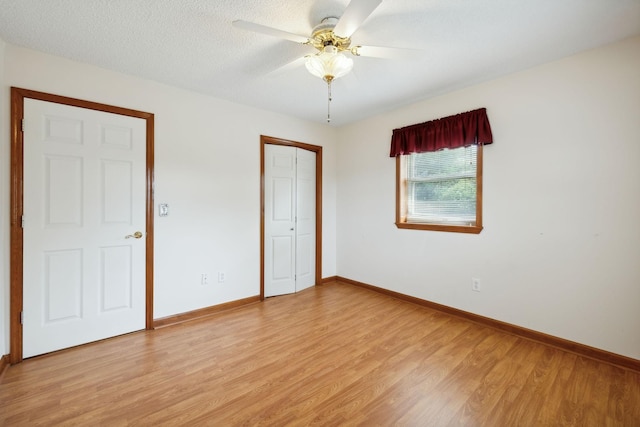 unfurnished bedroom featuring a textured ceiling, a ceiling fan, baseboards, a closet, and light wood finished floors