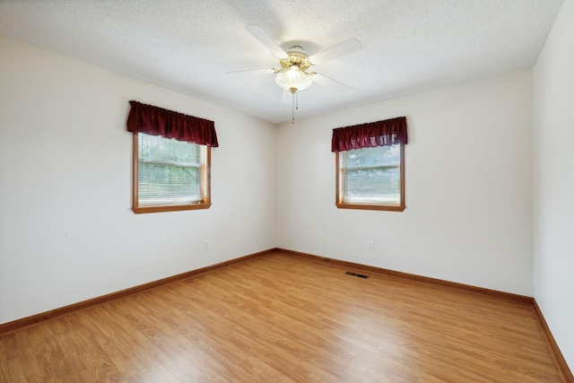 unfurnished room featuring light wood finished floors, visible vents, and baseboards