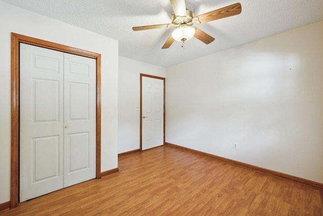 unfurnished bedroom with a textured ceiling, ceiling fan, baseboards, light wood-style floors, and a closet