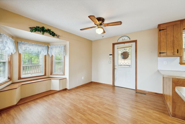 unfurnished dining area featuring visible vents, ceiling fan, light wood-style flooring, and baseboards