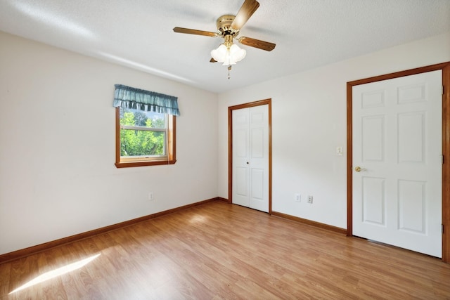 unfurnished bedroom featuring light wood finished floors, a closet, ceiling fan, a textured ceiling, and baseboards