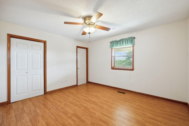 unfurnished bedroom with a textured ceiling, ceiling fan, visible vents, baseboards, and light wood finished floors