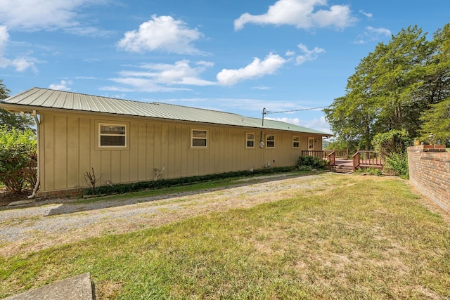 view of side of property featuring a deck, metal roof, and a lawn