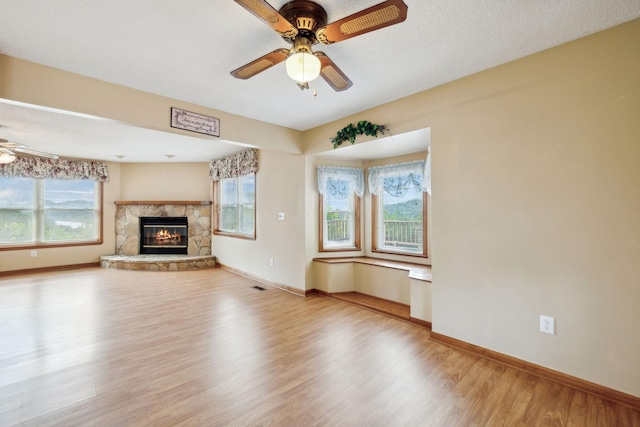 unfurnished living room featuring ceiling fan, baseboards, a wealth of natural light, and wood finished floors