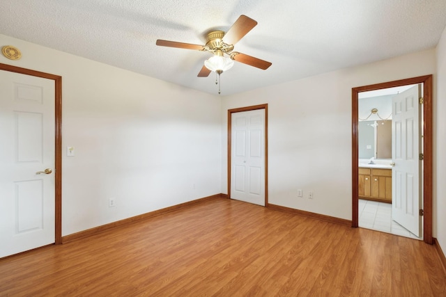 unfurnished bedroom with a textured ceiling, a sink, baseboards, light wood-style floors, and a closet