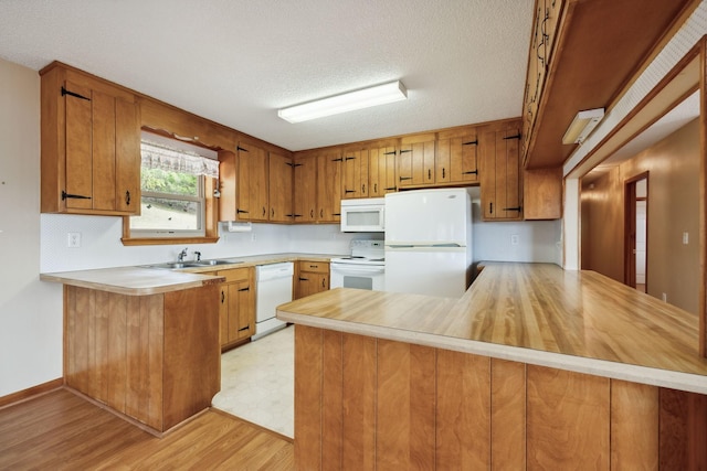 kitchen featuring a peninsula, white appliances, and light countertops