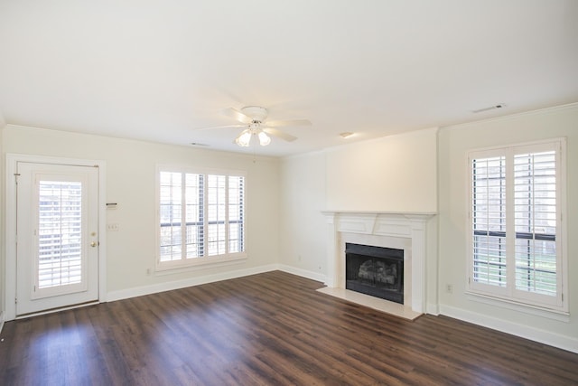 unfurnished living room with a fireplace with flush hearth, a wealth of natural light, dark wood-style flooring, and ornamental molding