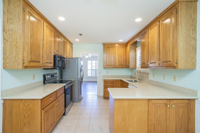 kitchen with a peninsula, light countertops, stainless steel range with electric stovetop, black microwave, and a sink