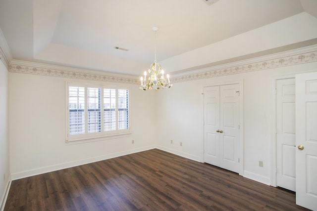 unfurnished room featuring a tray ceiling, dark wood-type flooring, and visible vents