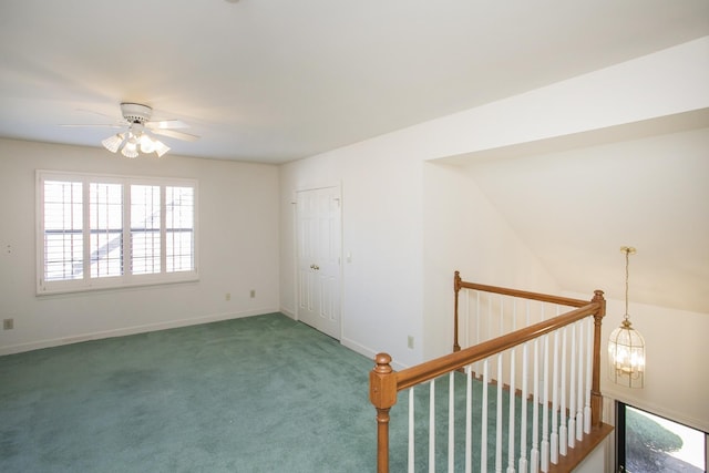 spare room with ceiling fan with notable chandelier, carpet, and baseboards