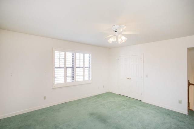 carpeted spare room featuring ceiling fan and baseboards