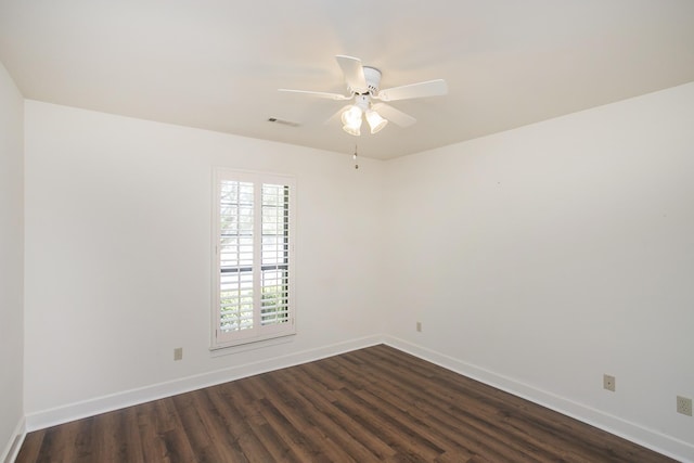 empty room featuring dark wood-style flooring, visible vents, ceiling fan, and baseboards