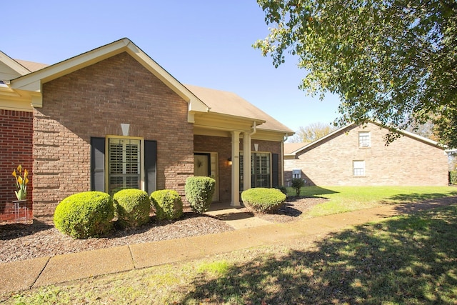 exterior space featuring brick siding and a lawn