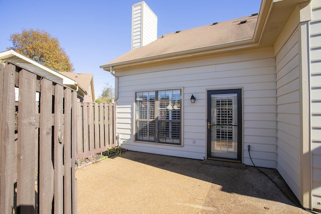 doorway to property featuring a patio area, a chimney, and fence