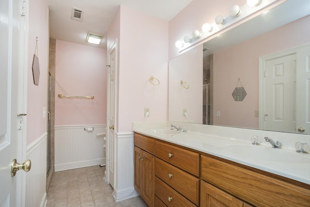 full bathroom featuring a wainscoted wall, a shower stall, visible vents, and a sink