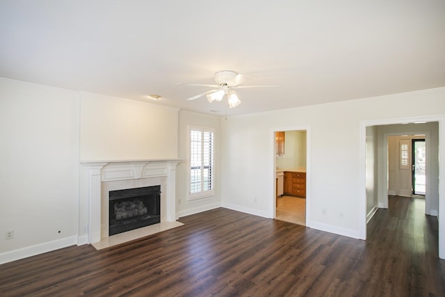 unfurnished living room with dark wood-style floors, a fireplace with flush hearth, ornamental molding, and baseboards