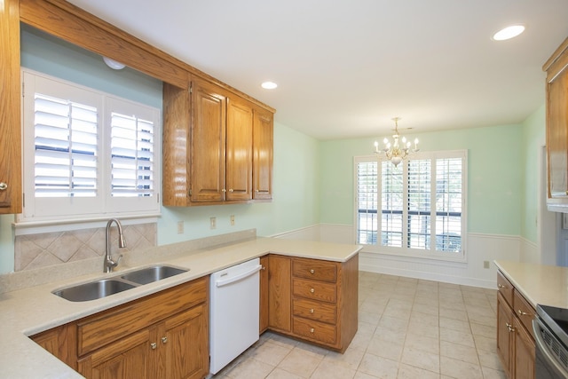 kitchen featuring white dishwasher, a peninsula, a sink, light countertops, and brown cabinets