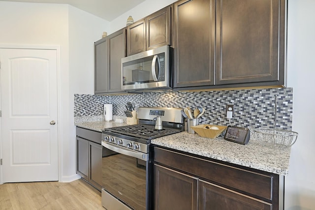 kitchen featuring appliances with stainless steel finishes, backsplash, light wood-style flooring, and dark brown cabinets