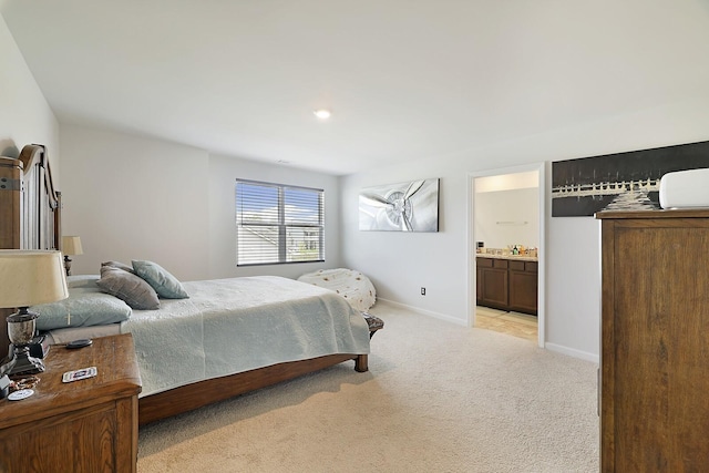 bedroom with baseboards, ensuite bathroom, and light colored carpet