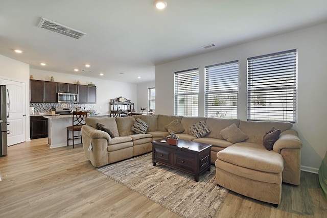 living room featuring light wood-type flooring, visible vents, and recessed lighting