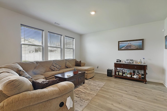 living area featuring baseboards, visible vents, and light wood finished floors