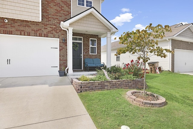 entrance to property with a garage, concrete driveway, covered porch, a yard, and brick siding