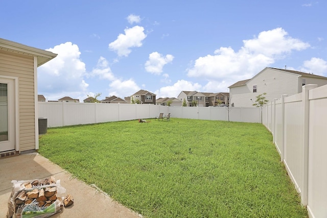 view of yard featuring a residential view, a fenced backyard, and central air condition unit