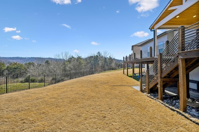 view of yard featuring a forest view, stairway, fence, and a wooden deck