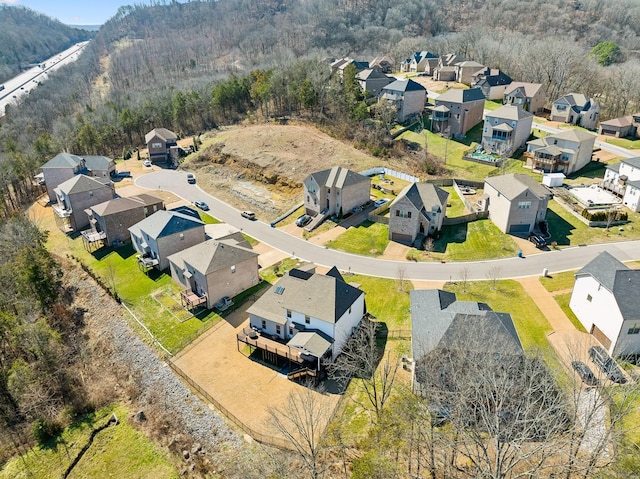 drone / aerial view featuring a wooded view and a residential view