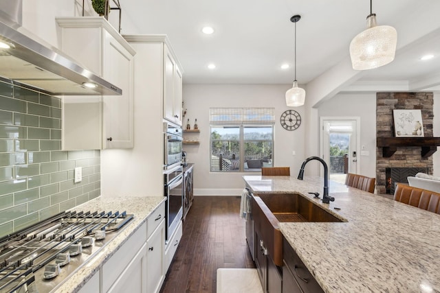 kitchen with stainless steel gas cooktop, white cabinets, wall chimney range hood, decorative backsplash, and dark wood finished floors