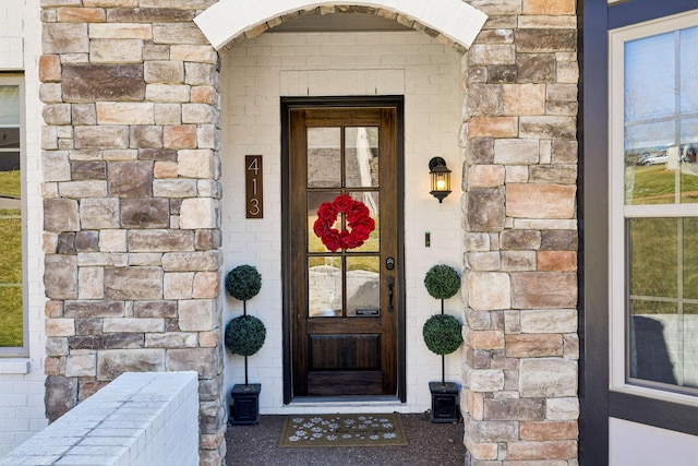 view of exterior entry featuring stone siding and brick siding