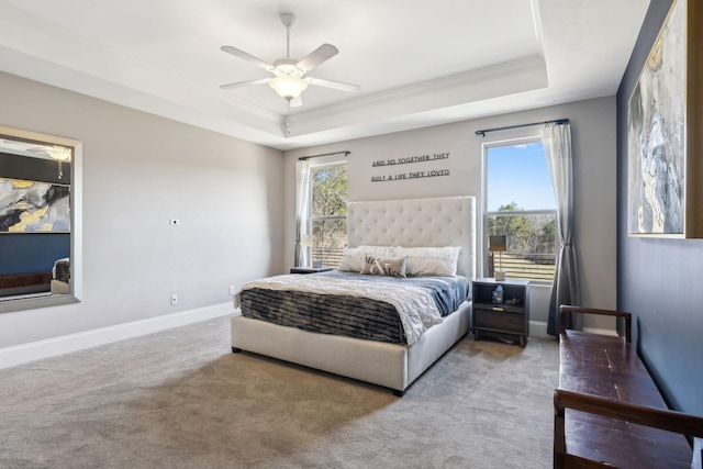 carpeted bedroom featuring crown molding, ceiling fan, a tray ceiling, and baseboards