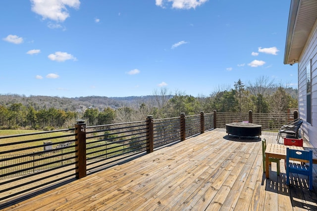 wooden deck with a fire pit and a view of trees