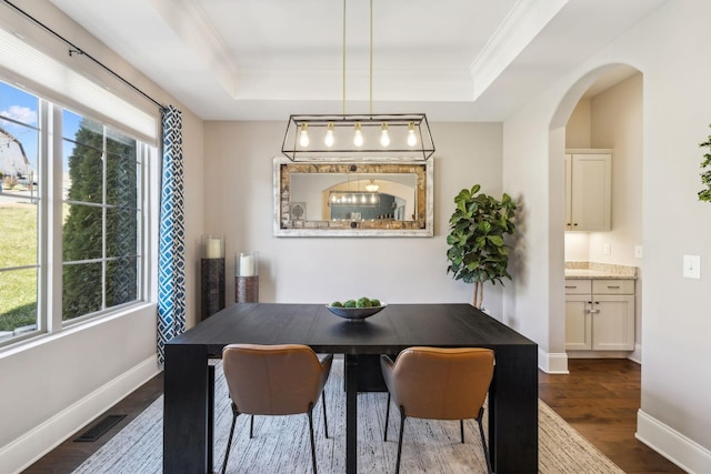 dining space with dark wood-style floors, a raised ceiling, visible vents, and crown molding