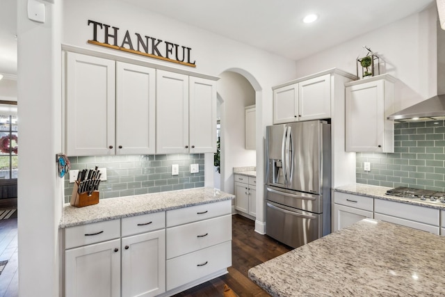 kitchen featuring dark wood-style floors, wall chimney exhaust hood, appliances with stainless steel finishes, and white cabinets