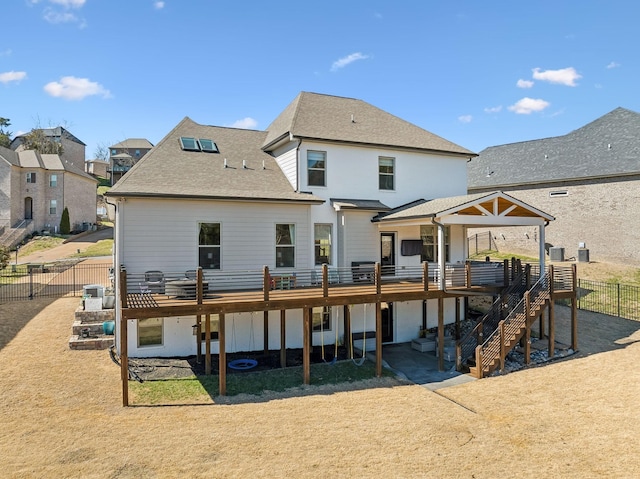 back of house with a deck, a shingled roof, stairway, and fence