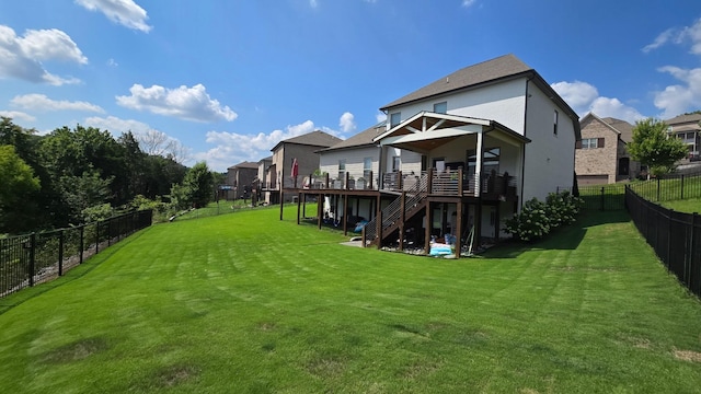 back of property with a fenced backyard, a lawn, stairway, and a wooden deck