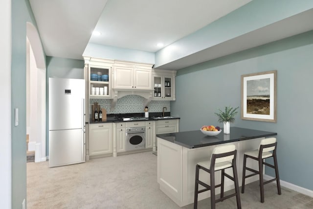 kitchen featuring backsplash, glass insert cabinets, oven, a kitchen breakfast bar, and fridge