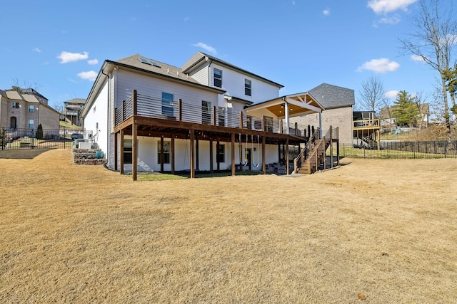 rear view of property featuring a deck, a yard, stairway, and fence private yard