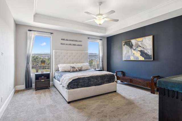 carpeted bedroom with a raised ceiling, crown molding, baseboards, and ceiling fan