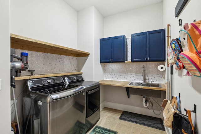 clothes washing area featuring cabinet space, light tile patterned floors, baseboards, independent washer and dryer, and a sink