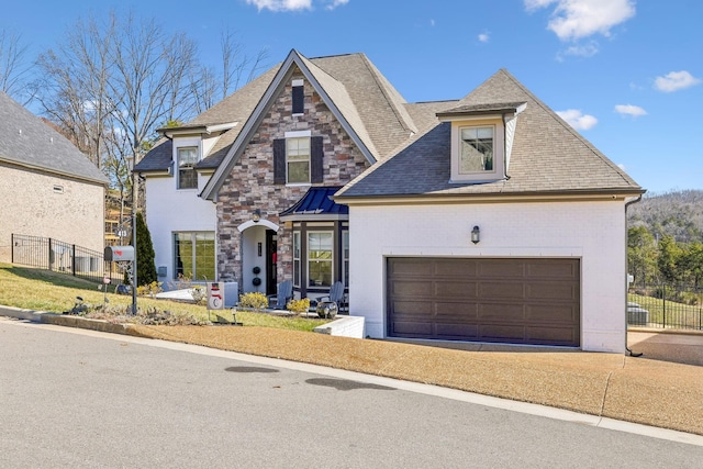 view of front of house with stone siding, concrete driveway, an attached garage, and fence