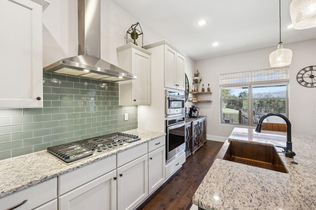 kitchen featuring stainless steel appliances, dark wood-style flooring, a sink, white cabinetry, and wall chimney exhaust hood